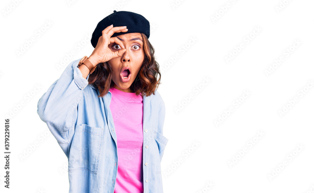 Young beautiful mixed race woman wearing french look with beret doing ok gesture shocked with surprised face, eye looking through fingers. unbelieving expression. Young beautiful mixed race woman wearing french look with beret doing ok gesture shocked with surprised face, eye looking through fingers. unbelieving expression.