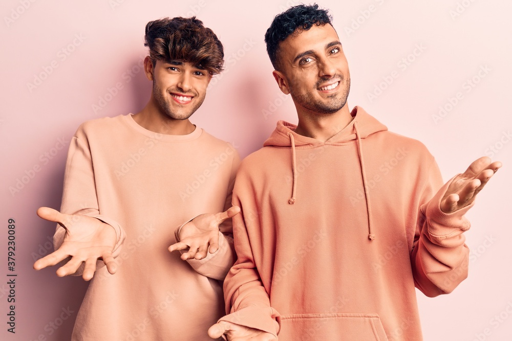 Young gay couple wearing casual clothes smiling cheerful with open arms as friendly welcome, positive and confident greetings Young gay couple wearing casual clothes smiling cheerful with open arms as friendly welcome, positive and confident greetings