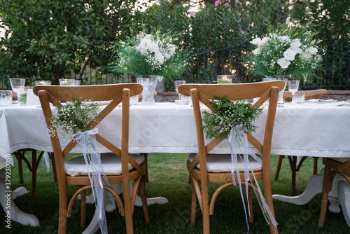Close-up of wedding chairs with decorated with white ribbons and flowers