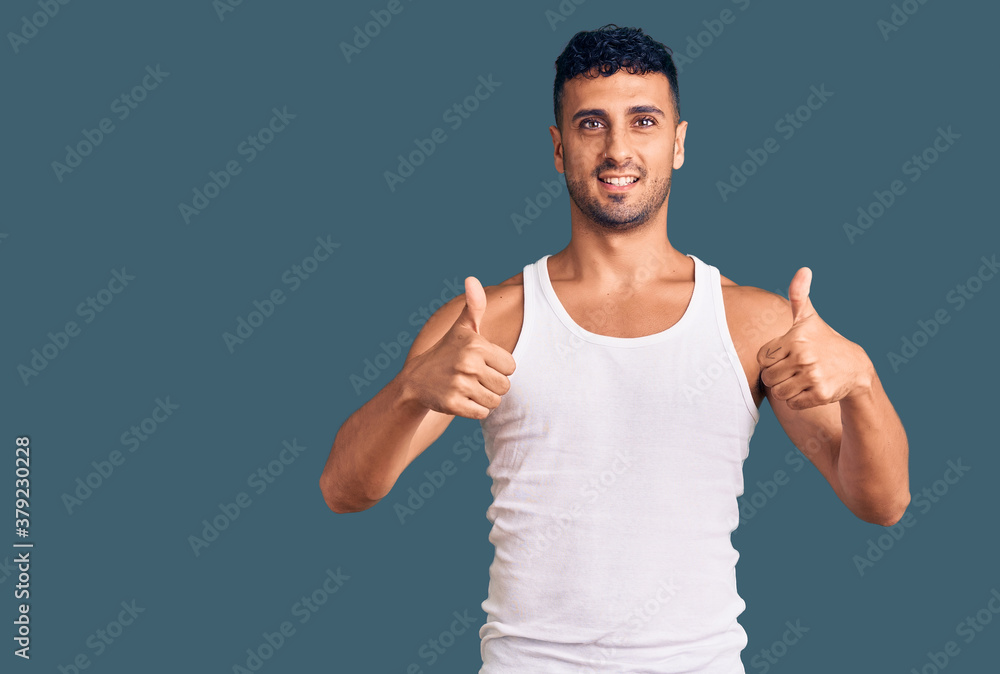 Fototapeta premium Young hispanic man wearing casual clothes success sign doing positive gesture with hand, thumbs up smiling and happy. cheerful expression and winner gesture.