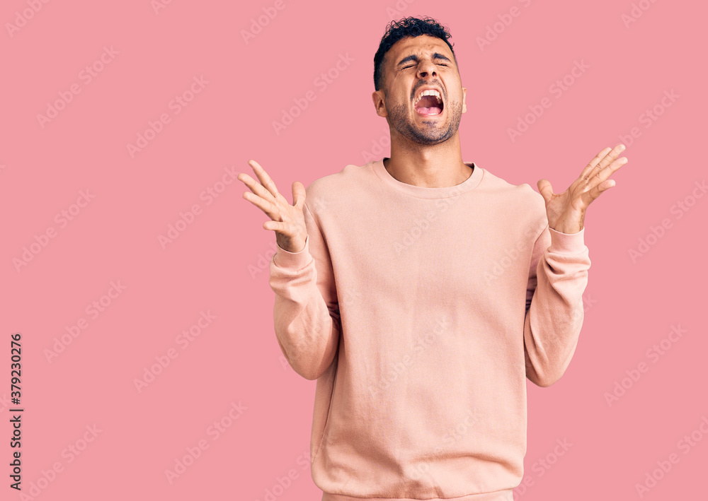 Young hispanic man wearing casual clothes celebrating mad and crazy for success with arms raised and closed eyes screaming excited. winner concept Young hispanic man wearing casual clothes celebrating mad and crazy for success with arms raised and closed eyes screaming excited. winner concept