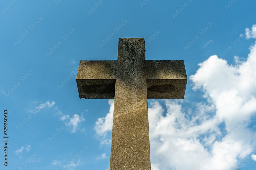 Large cross symbol made of stone against a blue sky