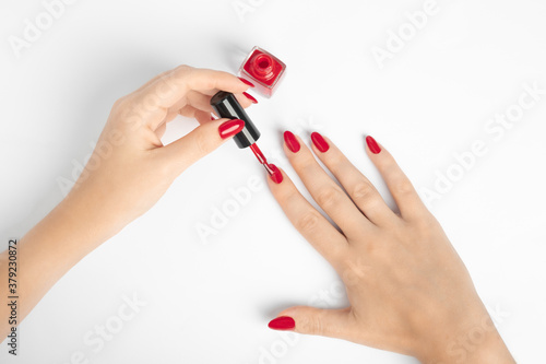 Fototapeta Woman applying red nail gel polish