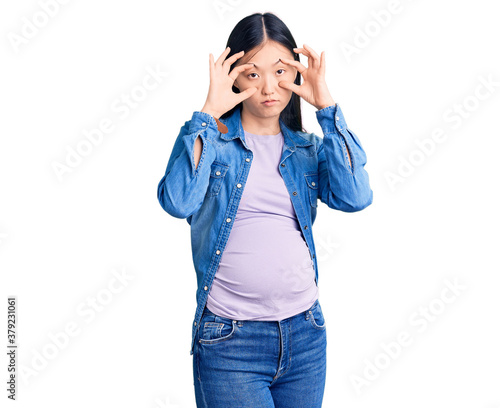 Young beautiful chinese woman pregnant expecting baby trying to open eyes with fingers, sleepy and tired for morning fatigue