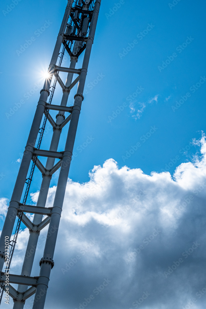 A tall communications tower with a beautiful blue sky and some clouds behind in the background. A tall communications tower with a beautiful blue sky and some clouds behind in the background.