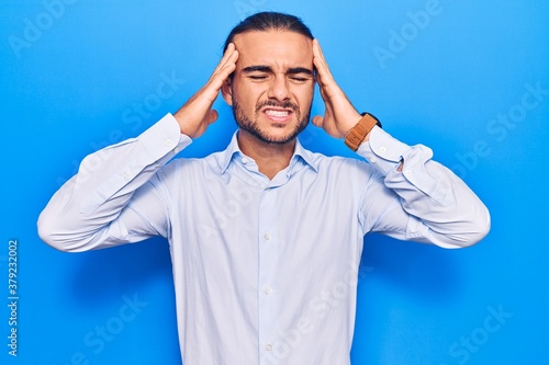 Young handsome man wearing business clothes with hand on head, headache because stress. suffering migraine.
