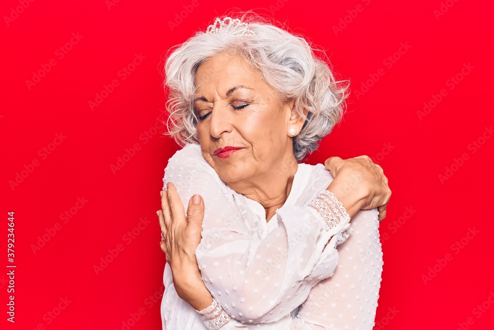 Senior grey-haired woman wearing casual clothes hugging oneself happy and positive, smiling confident. self love and self care