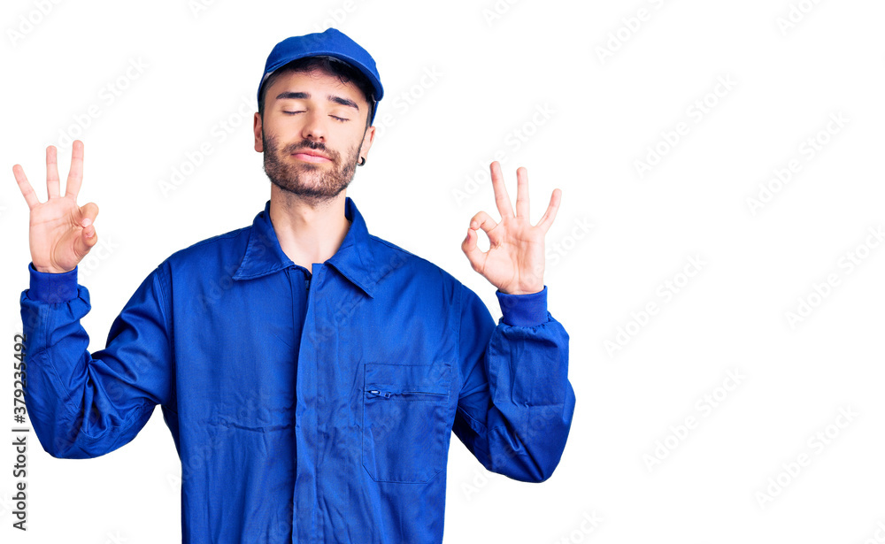 Young hispanic man wearing painter uniform relax and smiling with eyes closed doing meditation gesture with fingers. yoga concept. Young hispanic man wearing painter uniform relax and smiling with eyes closed doing meditation gesture with fingers. yoga concept.