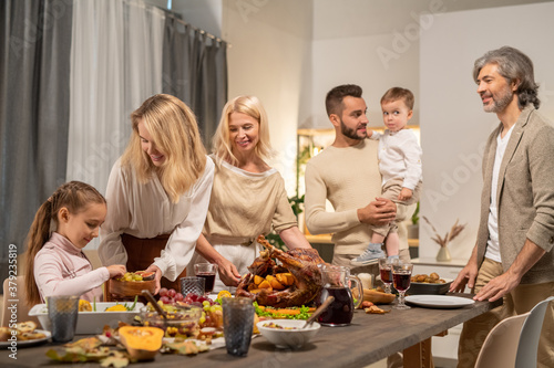 Young woman giving her little daughter fresh fruits among rest of the family