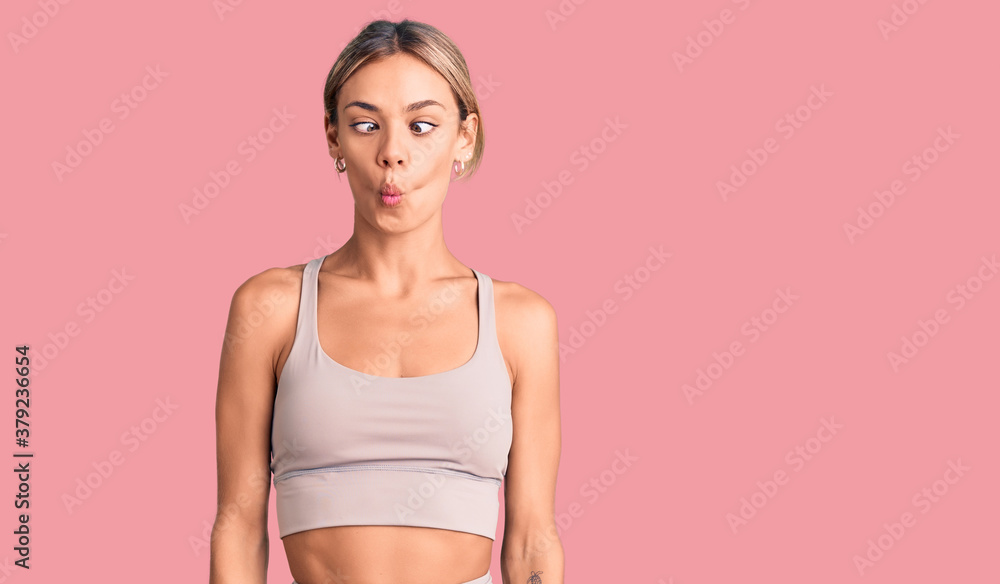 Beautiful caucasian woman wearing sportswear making fish face with lips, crazy and comical gesture. funny expression.