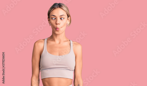 Beautiful caucasian woman wearing sportswear making fish face with lips, crazy and comical gesture. funny expression.