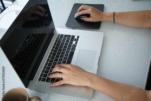 Top view of laptop in girl's hands sitting on a wooden floor with coffee, work from home or cafe, Hands writing ond a keyboard of a laptop or a notebook in Home Office