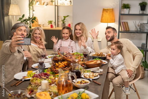 Happy large family of three generations waving hands by festive table