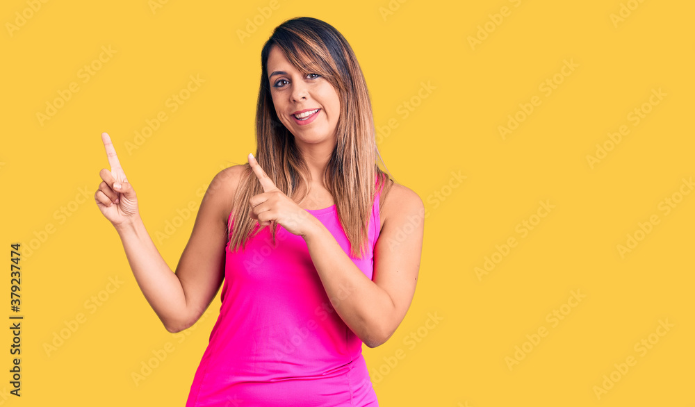 Young beautiful woman wearing sportswear smiling and looking at the camera pointing with two hands and fingers to the side. Young beautiful woman wearing sportswear smiling and looking at the camera pointing with two hands and fingers to the side.