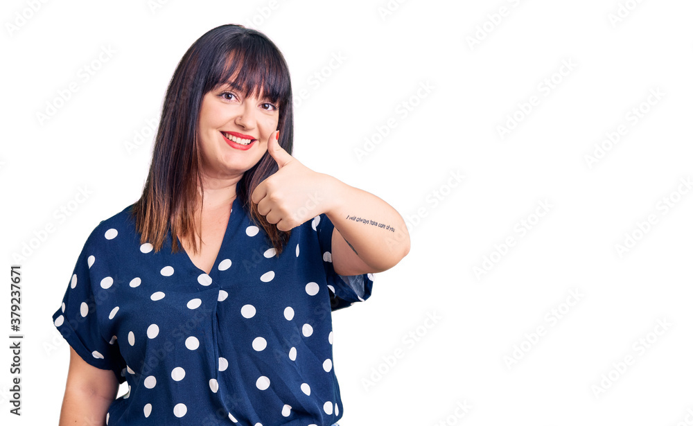 Young plus size woman wearing casual clothes doing happy thumbs up gesture with hand. approving expression looking at the camera showing success. Young plus size woman wearing casual clothes doing happy thumbs up gesture with hand. approving expression looking at the camera showing success.