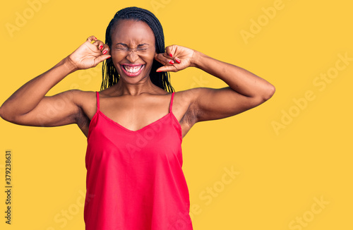 Young african american woman wearing casual clothes covering ears with fingers with annoyed expression for the noise of loud music. deaf concept.