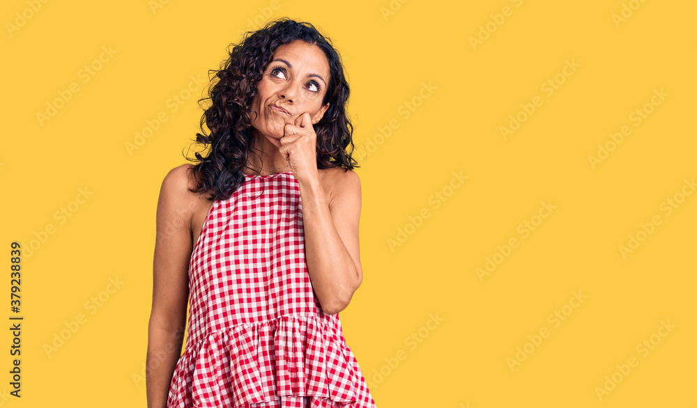 Middle age beautiful woman wearing casual sleeveless t shirt serious face thinking about question with hand on chin, thoughtful about confusing idea Middle age beautiful woman wearing casual sleeveless t shirt serious face thinking about question with hand on chin, thoughtful about confusing idea