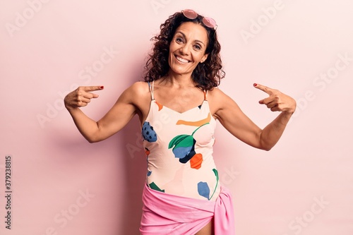 Obraz na plátně Middle age beautiful woman wearing swimwear and sunglasses looking confident with smile on face, pointing oneself with fingers proud and happy