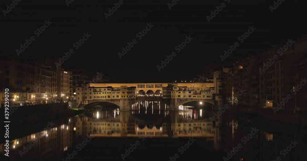 Wide shot of Ponte Vecchio during the night with the reflection on the Arno river Wide shot of Ponte Vecchio during the night with the reflection on the Arno river