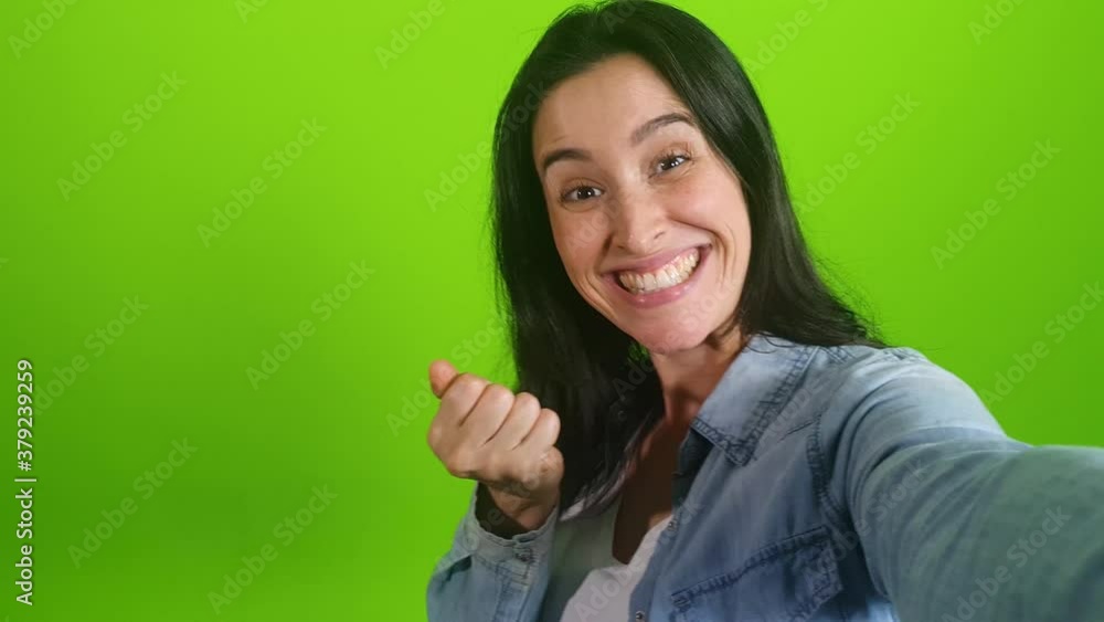 smiling woman posing on green screen background. Girl making a video call self portrait photo on smartphone. Chroma key. Female model showing positive face emotions
smiling woman posing on green screen background. Girl making a video call self portrait photo on smartphone. Chroma key. Female model showing positive face emotions