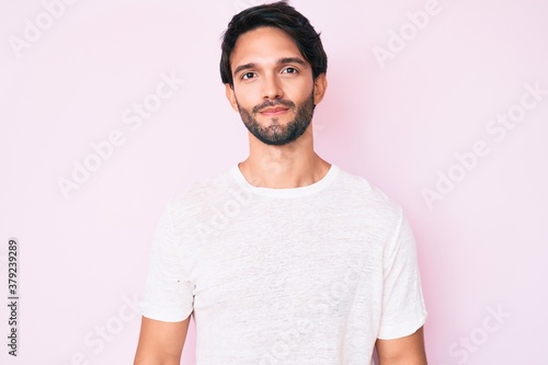 Handsome hispanic man wearing casual white tshirt with serious expression on face. simple and natural looking at the camera. © Krakenimages.com