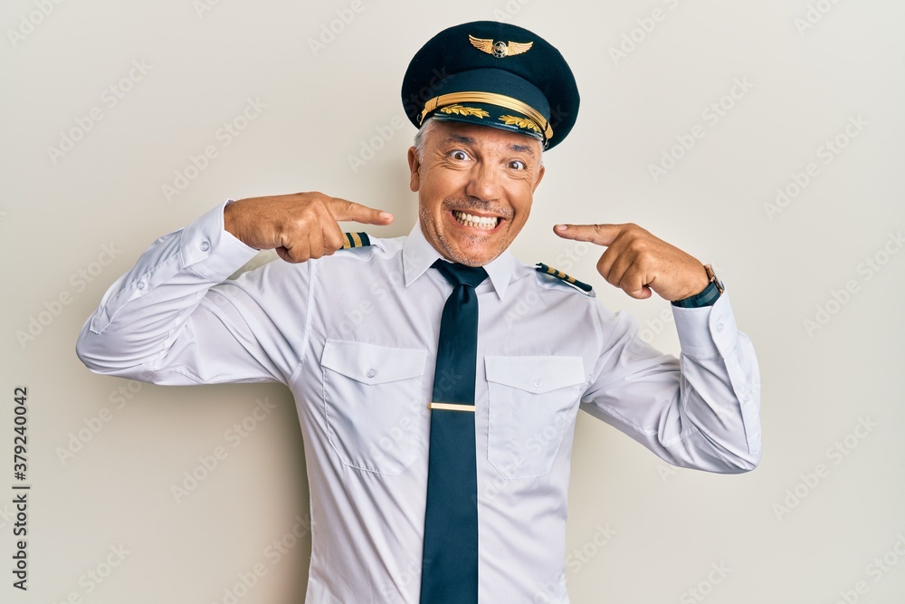Handsome middle age mature man wearing airplane pilot uniform smiling cheerful showing and pointing with fingers teeth and mouth. dental health concept.