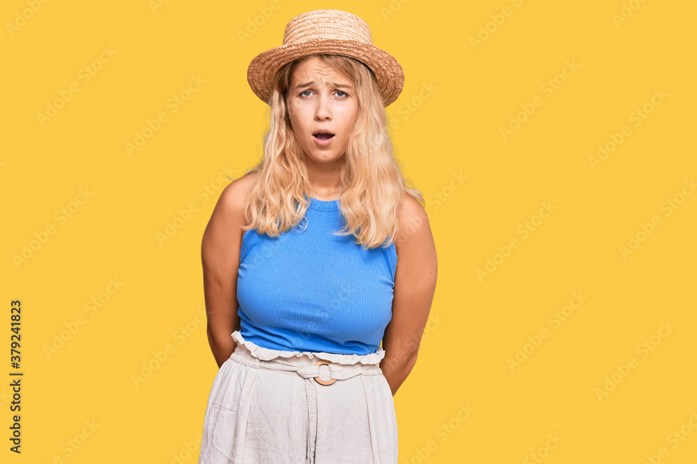 Young blonde girl wearing summer hat scared and amazed with open mouth for surprise, disbelief face Young blonde girl wearing summer hat scared and amazed with open mouth for surprise, disbelief face