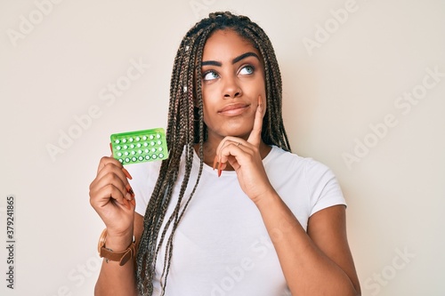 Tableau sur toile Young african american woman with braids holding birth control pills serious fac
