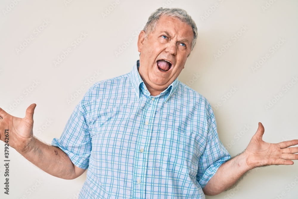 Senior grey-haired man wearing casual clothes crazy and mad shouting and yelling with aggressive expression and arms raised. frustration concept. Senior grey-haired man wearing casual clothes crazy and mad shouting and yelling with aggressive expression and arms raised. frustration concept.