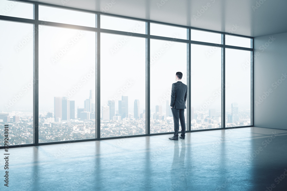 Young businessman looking on window in contemporary office Young businessman looking on window in contemporary office