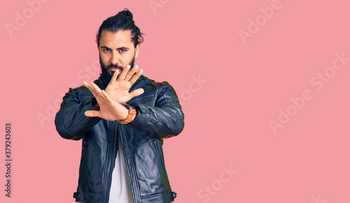 Young arab man wearing casual leather jacket rejection expression crossing arms doing negative sign, angry face