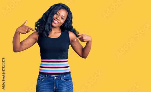 Beautiful african american woman wearing casual clothes looking confident with smile on face, pointing oneself with fingers proud and happy.