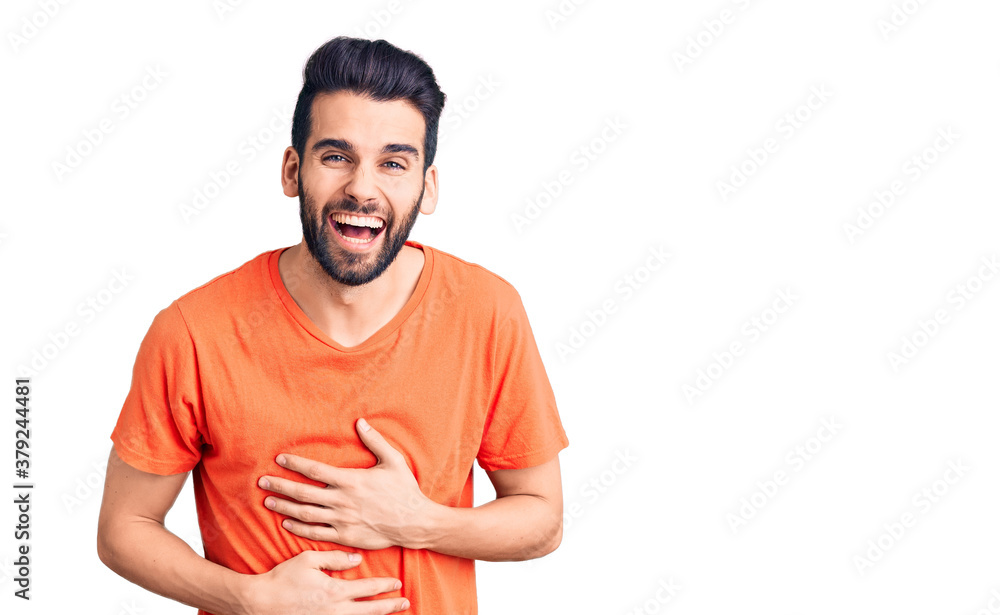 Fototapeta premium Young handsome man with beard wearing casual t-shirt smiling and laughing hard out loud because funny crazy joke with hands on body.