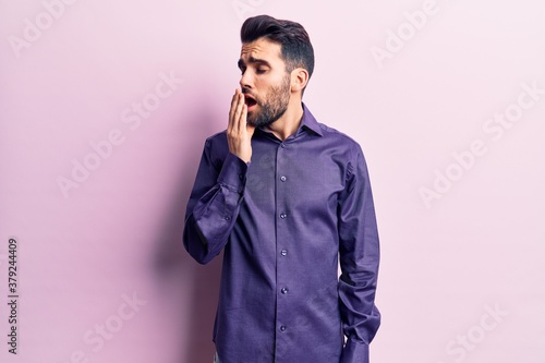 Young handsome man with beard wearing casual shirt bored yawning tired covering mouth with hand. restless and sleepiness. © Krakenimages.com