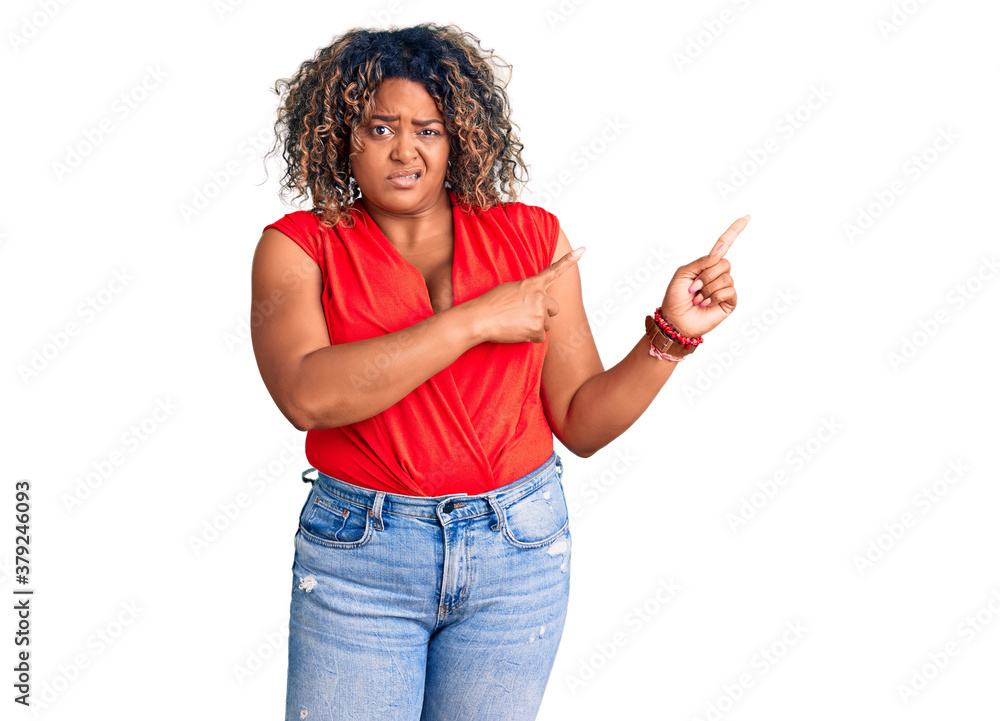 Young african american plus size woman wearing casual style with sleeveless shirt pointing aside worried and nervous with both hands, concerned and surprised expression Young african american plus size woman wearing casual style with sleeveless shirt pointing aside worried and nervous with both hands, concerned and surprised expression