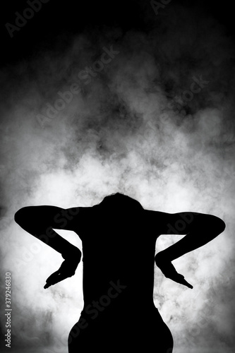 silhouette modern ballet dancer posing on dark background with smoke