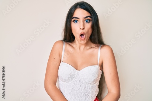Brunette teenager girl posing elegant afraid and shocked with surprise expression, fear and excited face.