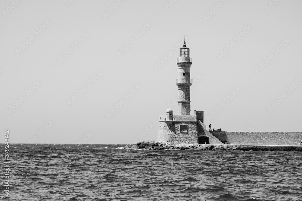 Black and white image of a lighthouse standing at the entrance to the old harbour in Chania, Crete. Black and white image of a lighthouse standing at the entrance to the old harbour in Chania, Crete.