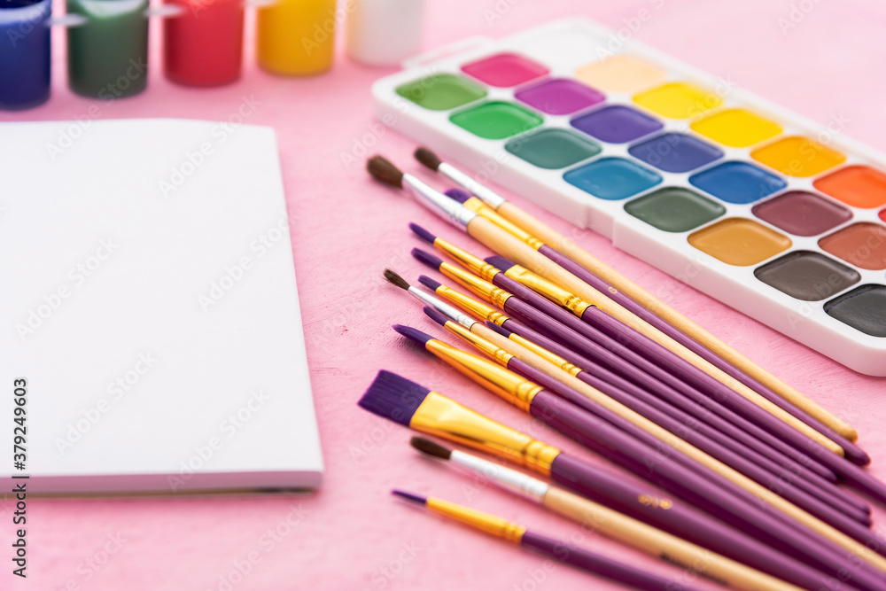 Fototapeta premium Watercolor paints and brushes for drawing on a pink background. Copy space.