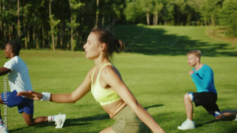 Three athletic people with professional female coach actively training outdoors performing intense physical exercises in sports ground. People in sports. Nature concept. Three athletic people with professional female coach actively training outdoors performing intense physical exercises in sports ground. People in sports. Nature concept.