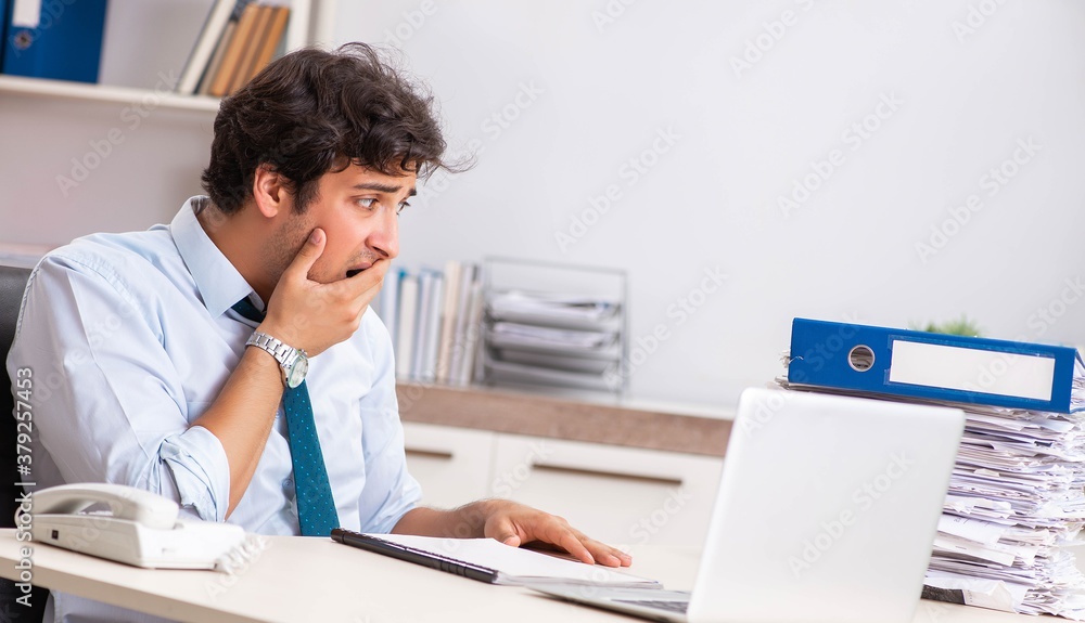 Overloaded busy employee with too much work and paperwork Overloaded busy employee with too much work and paperwork