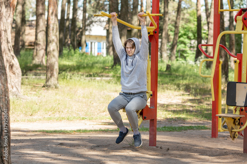 Single young man doing exercises on the sports ground in the park, street workout. Fitness outside. Exercising alone for Covid-19 prevention - Image