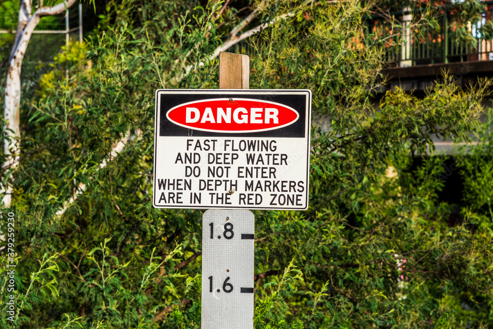 A danger flood sign with the words fast flowing and deep water, do not enter when depth markers are in the red zone