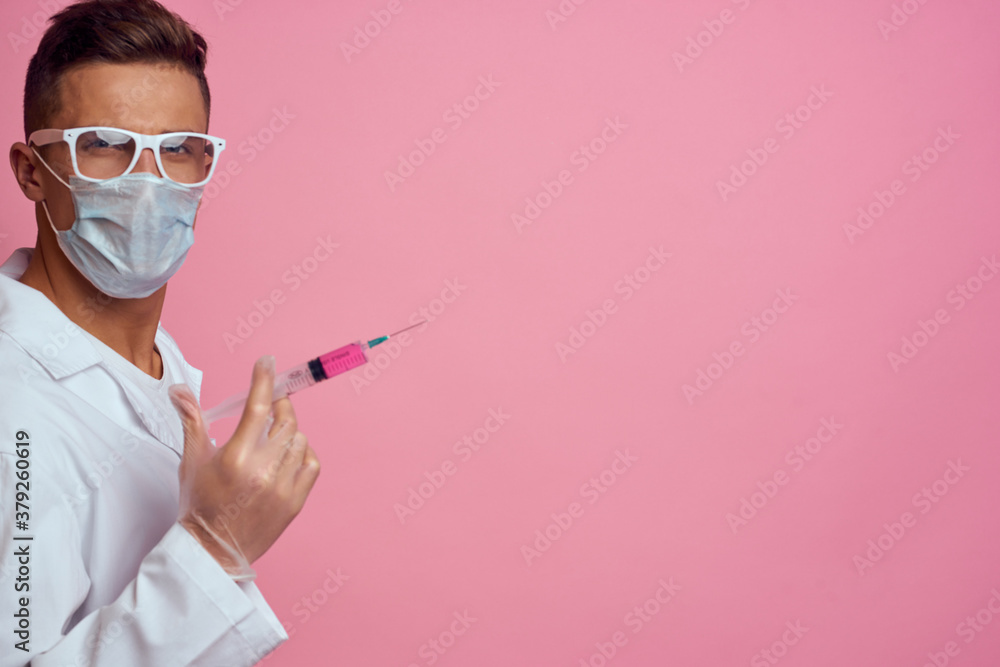 A doctor in a medical mask and gloves holds a syringe in the hands of an injection laboratory A doctor in a medical mask and gloves holds a syringe in the hands of an injection laboratory
