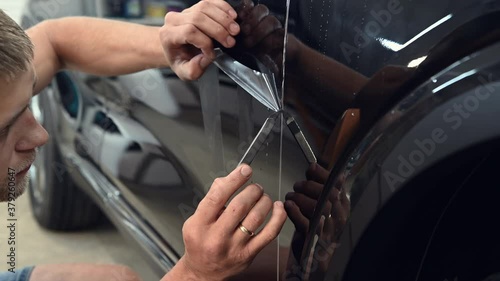 Cutting paint protection film with a special knife tool on a black car