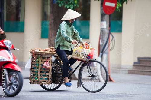 Hanoi, Vietnam - November 21, 2019: Street vendors are hurriedly cycling across the street to find customers in the small neighborhood in Hanoi, Vietnam