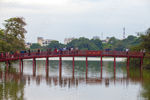 Hanoi, Vietnam - October 21, 2019 : Hanoi red bridge. The wooden red painted bridge over the Hoan Kiem Lake connects the shore and the Jade Island on which Ngoc Son Temple stands. © binhdd