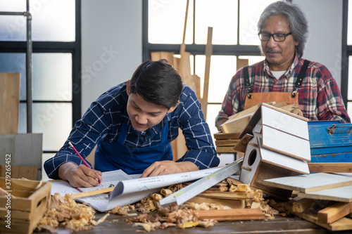 Young and senoir carpenters working and training on wood craft handmade using professional tools at workshop to produce construction material or wooden furniture . DIY maker and carpentry concept