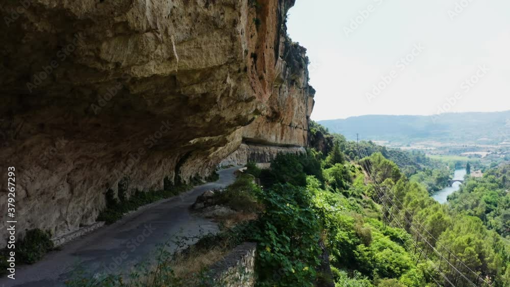 Dolly in aerial shot of Mirador el Puente Romano road and forested hill. Dolly in aerial shot of Mirador el Puente Romano road and forested hill.