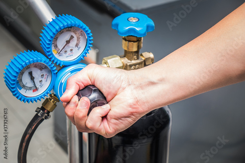 Man close operating valve of welding equipment acetylene gas cylinder with pressure gauges on the oxygen tank. photo